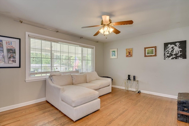 living area with light wood-style floors, a ceiling fan, and baseboards