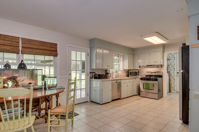 kitchen featuring appliances with stainless steel finishes, a sink, light countertops, light tile patterned floors, and under cabinet range hood