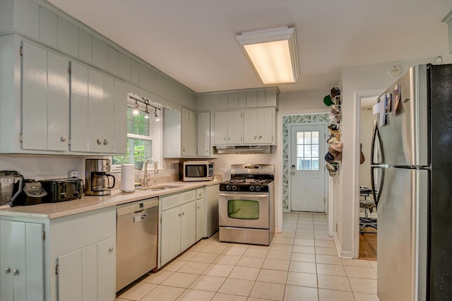 kitchen featuring plenty of natural light, a sink, under cabinet range hood, and stainless steel appliances