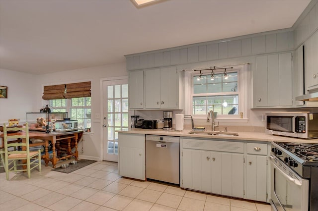 kitchen featuring a sink, light countertops, stainless steel appliances, a healthy amount of sunlight, and under cabinet range hood