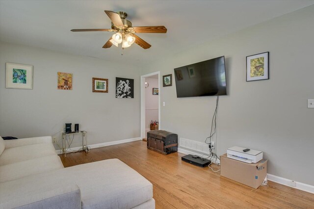 living room with baseboards, a ceiling fan, and wood finished floors