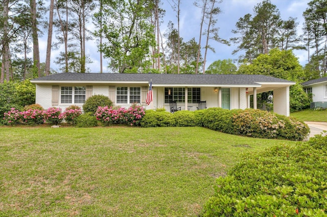 ranch-style house featuring concrete driveway, brick siding, a front yard, and an attached carport