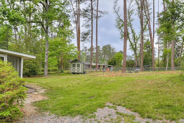 view of yard featuring a storage shed, fence, and an outbuilding