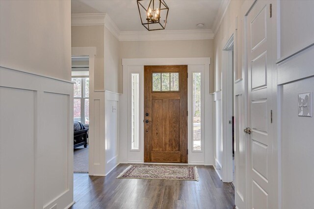 foyer entrance featuring a notable chandelier, dark hardwood / wood-style floors, a healthy amount of sunlight, and ornamental molding