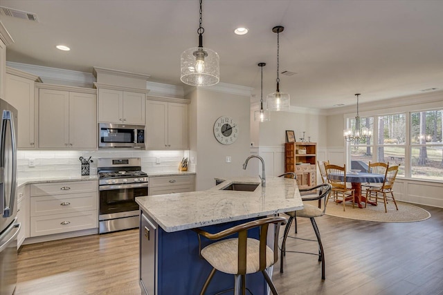 kitchen featuring pendant lighting, sink, stainless steel appliances, and a center island with sink