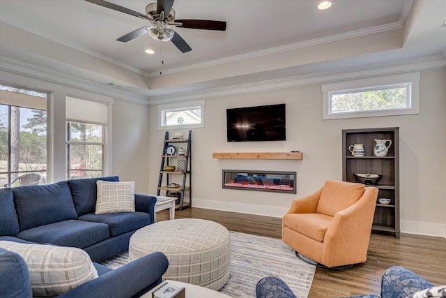 living room with a raised ceiling, hardwood / wood-style floors, a healthy amount of sunlight, and ornamental molding