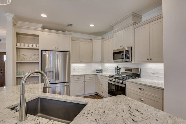 kitchen featuring decorative backsplash, light stone countertops, sink, and appliances with stainless steel finishes