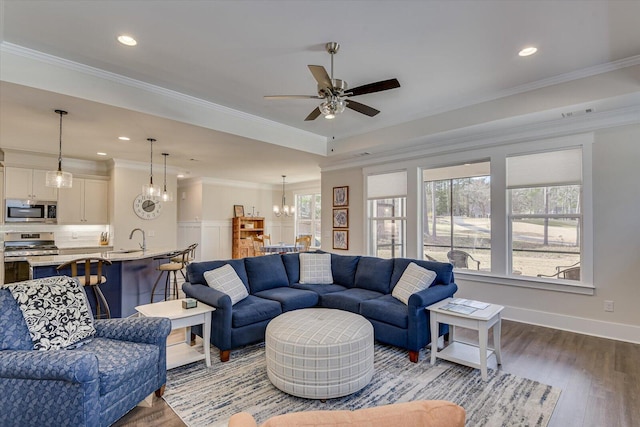 living room featuring crown molding, sink, ceiling fan with notable chandelier, and hardwood / wood-style flooring