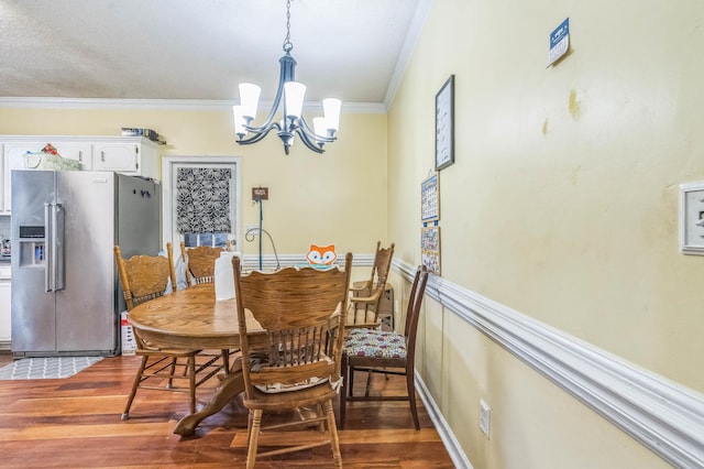 dining space featuring a chandelier, ornamental molding, and wood finished floors