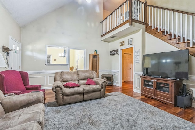 living area featuring wood finished floors, high vaulted ceiling, stairway, and wainscoting