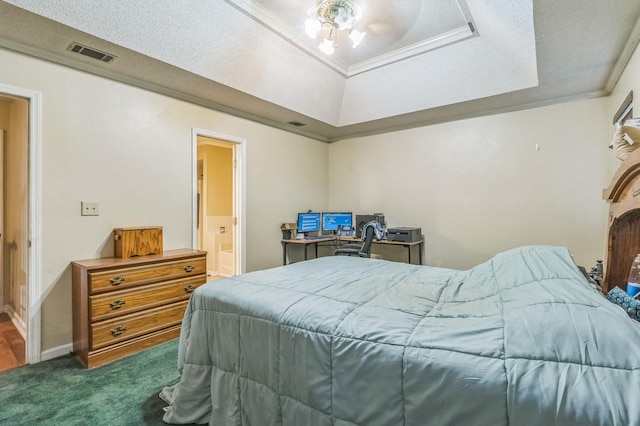 carpeted bedroom with a tray ceiling and ensuite bath
