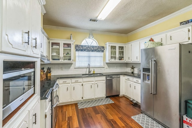 kitchen featuring appliances with stainless steel finishes, a sink, dark countertops, a textured ceiling, and dark wood-style floors