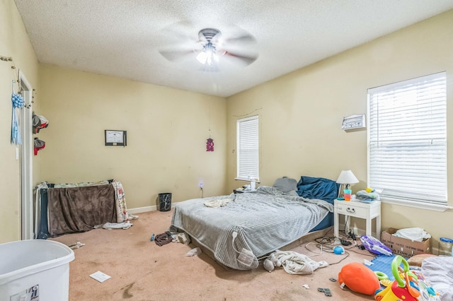 bedroom featuring carpet floors, multiple windows, ceiling fan, a textured ceiling, and baseboards