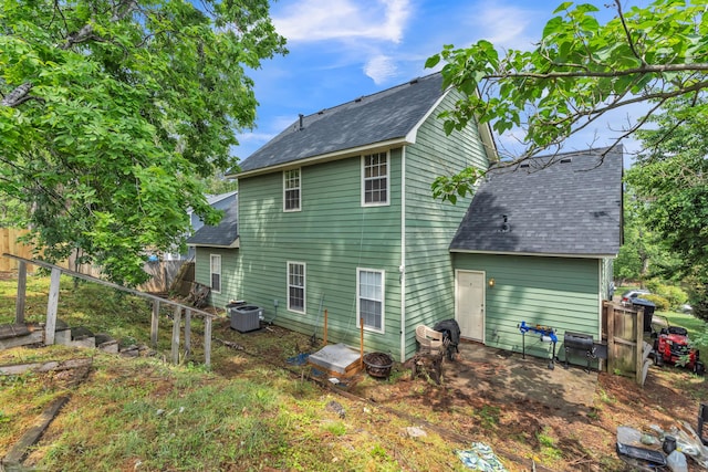 rear view of house featuring a shingled roof, central AC, and fence