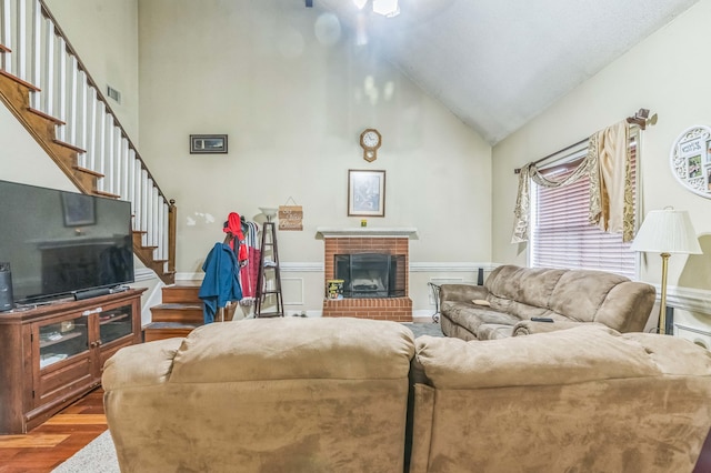 living room featuring stairway, wood finished floors, high vaulted ceiling, and a fireplace
