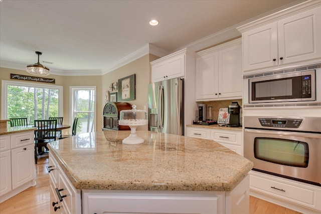 209 Apple Ln, Mccormick, SC 29835 - kitchen featuring appliances with stainless steel finishes, a kitchen island, crown molding, light stone countertops, and white cabinetry