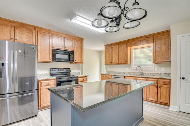 2030 Lake Forest Dr, Grovetown, GA 30813 - kitchen with black appliances, light wood finished floors, a chandelier, stone counters, and a kitchen island