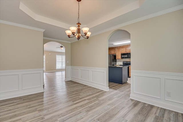 2030 Lake Forest Dr, Grovetown, GA 30813 - empty room with arched walkways, a raised ceiling, a chandelier, light wood-style flooring, and a decorative wall