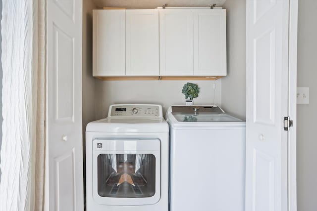 washroom with washing machine and clothes dryer and cabinet space