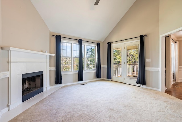 unfurnished living room with visible vents, ceiling fan, carpet, a tiled fireplace, and high vaulted ceiling