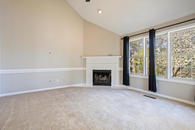 unfurnished living room with visible vents, a fireplace with flush hearth, high vaulted ceiling, carpet flooring, and baseboards