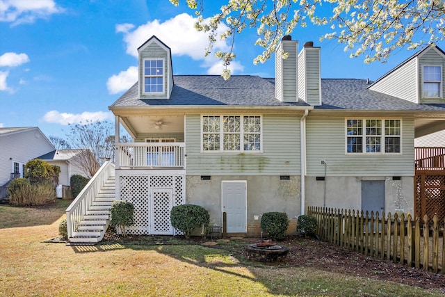 back of property with stairway, an outdoor fire pit, a yard, and fence