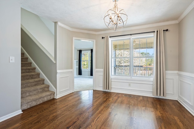 unfurnished dining area with a notable chandelier, wood finished floors, stairway, wainscoting, and crown molding