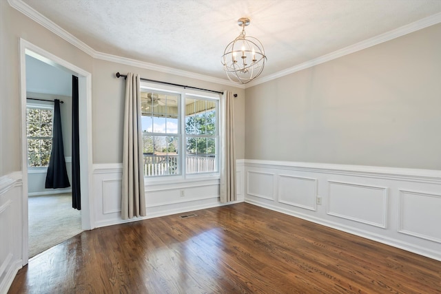 unfurnished room with visible vents, dark wood-style flooring, ornamental molding, wainscoting, and a chandelier