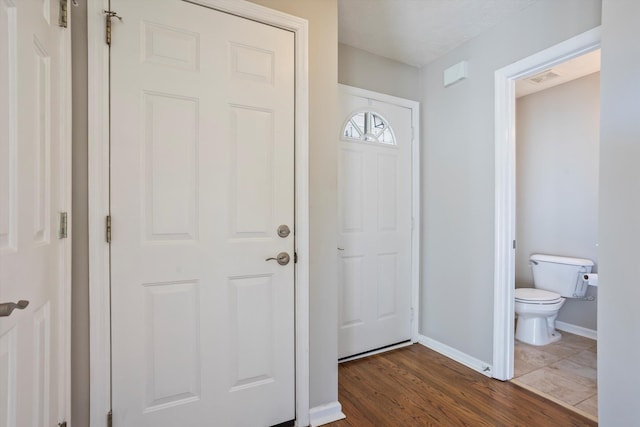 interior space featuring toilet, wood finished floors, visible vents, and baseboards