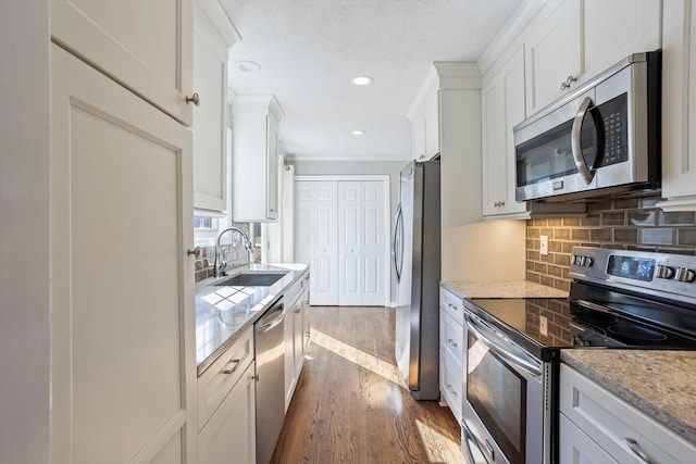 kitchen featuring dark wood-type flooring, a sink, tasteful backsplash, white cabinetry, and stainless steel appliances