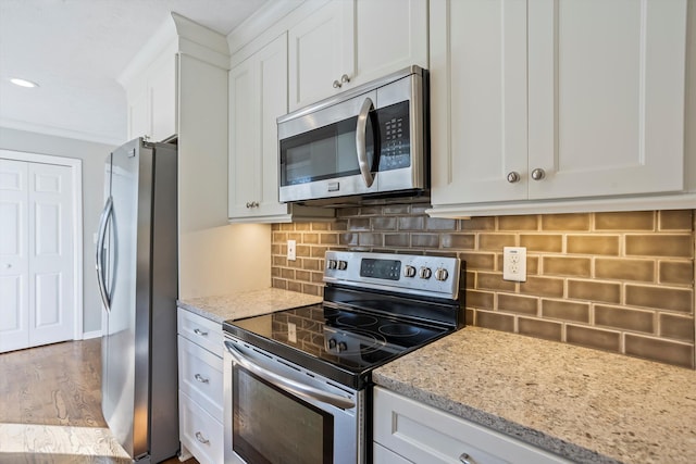 kitchen featuring backsplash, light stone countertops, appliances with stainless steel finishes, wood finished floors, and white cabinets