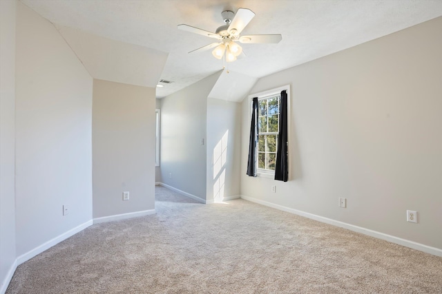 spare room with a ceiling fan, baseboards, visible vents, carpet floors, and lofted ceiling