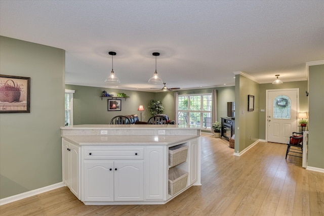 138 Evergreen Ln, Mccormick, SC 29835 - kitchen with light countertops, a peninsula, white cabinetry, hanging light fixtures, and light wood-type flooring