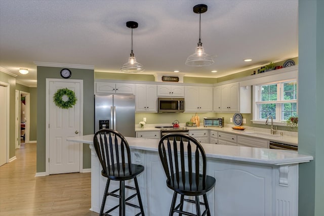 138 Evergreen Ln, Mccormick, SC 29835 - kitchen featuring appliances with stainless steel finishes, a sink, white cabinetry, a kitchen bar, and ornamental molding