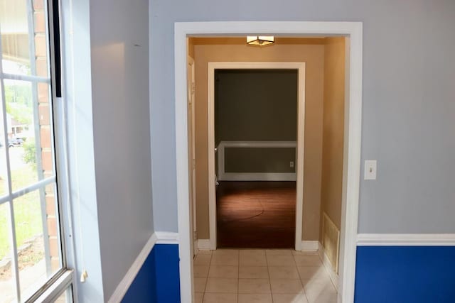hall with plenty of natural light, baseboards, light tile patterned floors, and visible vents