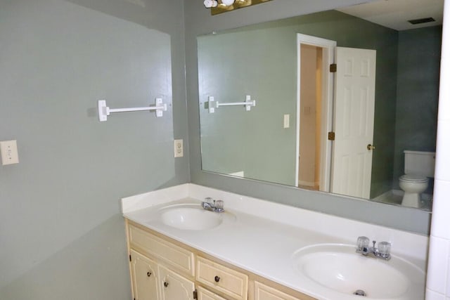 bathroom featuring visible vents, a sink, double vanity, and toilet