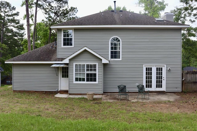 back of house with a lawn, a shingled roof, a chimney, and a patio area