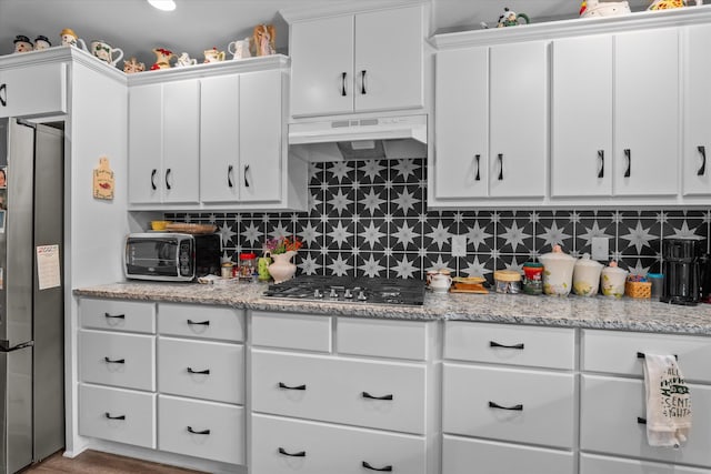 3604 Hillman Gay Rd, Dearing, GA 30808 - kitchen with stainless steel appliances, under cabinet range hood, white cabinets, tasteful backsplash, and light stone counters
