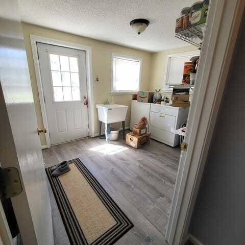 laundry area with wood finished floors, laundry area, a sink, a textured ceiling, and washer and dryer