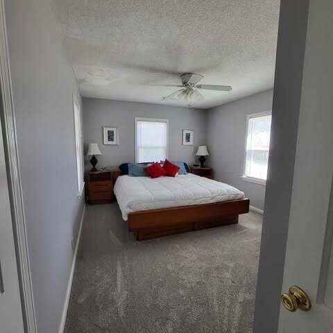 bedroom featuring light colored carpet, baseboards, and a textured ceiling