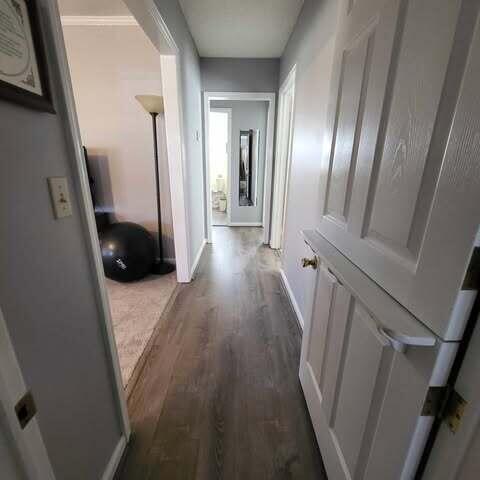 corridor featuring wood finished floors and baseboards