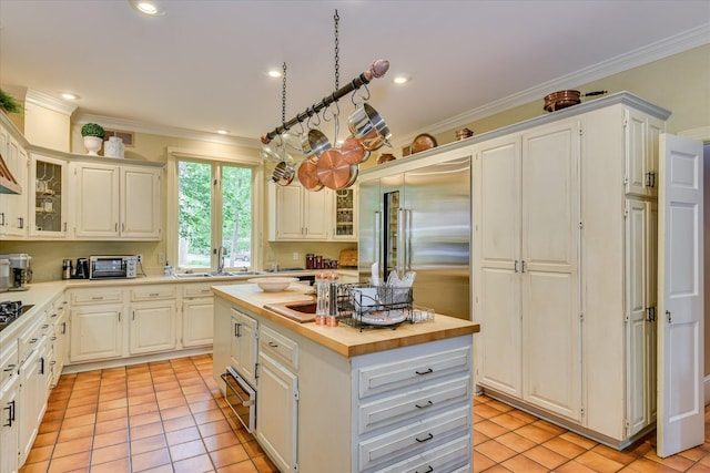 8 Tall Pine Ct, Augusta, GA 30909 - kitchen with butcher block counters, a center island, crown molding, light tile patterned flooring, and glass insert cabinets