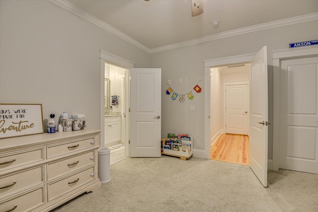 bedroom with light carpet, crown molding, baseboards, and ensuite bathroom