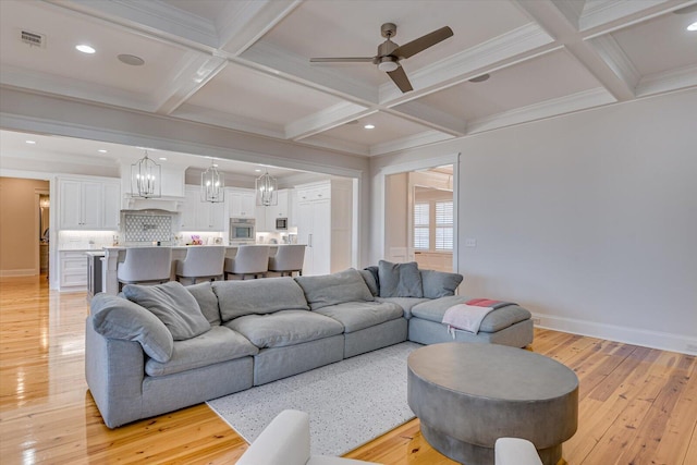 living area with beam ceiling, coffered ceiling, and light wood-style flooring