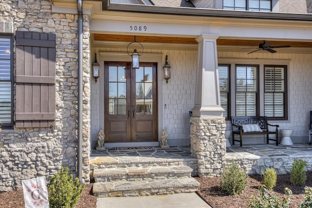 view of exterior entry with a porch, french doors, a shingled roof, and stone siding