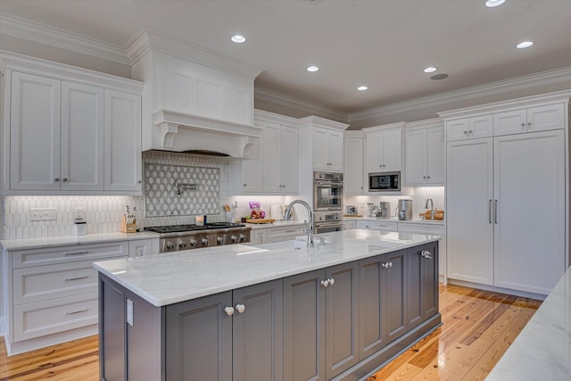 kitchen with stainless steel appliances, light wood finished floors, a sink, and white cabinets