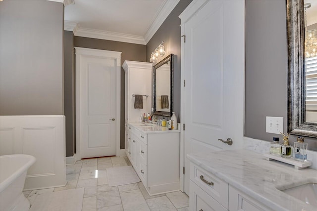 bathroom with a freestanding tub, a sink, two vanities, marble finish floor, and ornamental molding