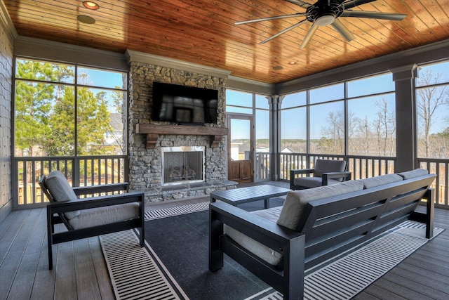 sunroom / solarium with ceiling fan, a fireplace, and wood ceiling