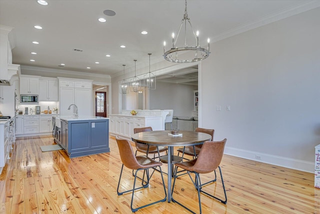 dining room featuring a notable chandelier, light wood finished floors, baseboards, and crown molding