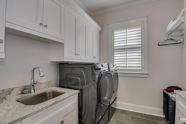 laundry room featuring a sink, baseboards, cabinet space, washer and clothes dryer, and crown molding